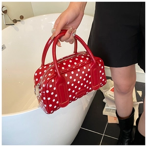 Detailed close-up of glossy red polka dot Boston bag with metal zipper and logo