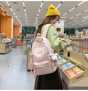 Lifestyle view of light pink casual backpack with stylish tassels in a shopping store