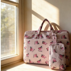 Close-up of pink velvet laptop sleeve set with butterfly print on a sunny windowsill