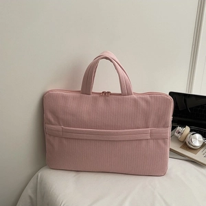 Pink corduroy laptop bag with top handles shown with headphones and notebook accessories