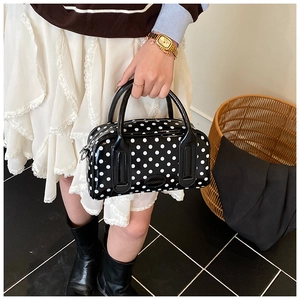 Close-up of black and white polka dot boston bag with glossy patent leather finish