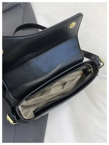 Detail of black leather saddle bag interior showing gold hardware and zip pocket