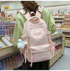 Detailed pink backpack featuring bow embroidery and a white plush animal charm