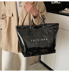 Detail of glossy black patent leather tote bag with white TOTE BAG lettering design