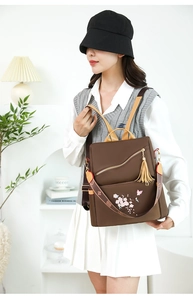 Détail du sac à dos oxford marron foncé avec broderie ethnique et charm à pompon