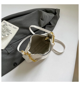 Detailed view of white ostrich texture handbag with golden chain and zipper opening