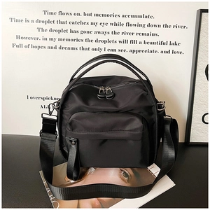 Minimalist black nylon crossbody bag with dual-zipper front pocket and adjustable strap