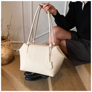 Minimalist beige pebble leather tote bag shown in a lifestyle urban scene on stairs