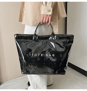 Detail shot of black glossy tote bag with faux snakeskin texture and TOTE BAG lettering