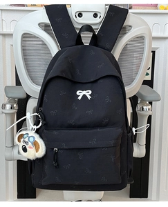 Detail of black backpack with butterfly pattern and white 3D bow with plush dog pendant