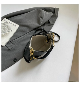 Detail view of black ostrich texture handbag showing interior lining and golden hardware