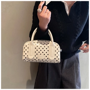Close-up of a white polka dot Boston handbag with OROBOOMI logo held by a model