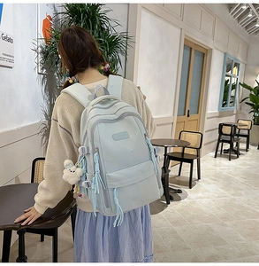 Detail view of large mint green canvas backpack with adjustable straps and plush charm