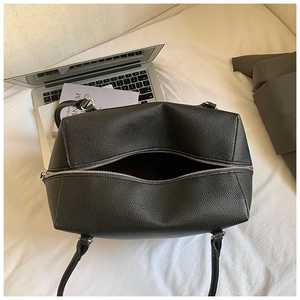 Close-up of black pebble leather tote with silver zipper and spacious interior compartment