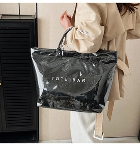 Detail of glossy black faux snake skin tote bag with white TOTE BAG lettering design