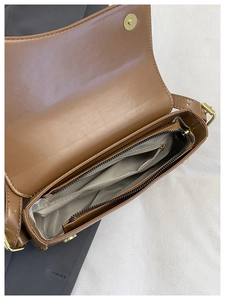 Detail of brown leather bag interior showing magnetic buckle and zigzag lining