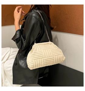Vista lateral del bolso de cadena trenzado crema usado por modelo con cuero