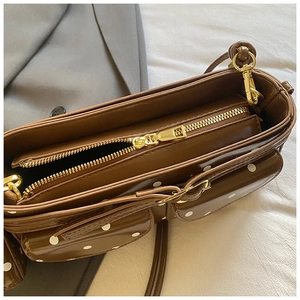 Detailansicht der braunen Tasche mit Pünktchen, Goldbeschlägen und Reißverschluss