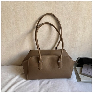 Borsa bowling in pelle marrone con manici lunghi, mostrata con un computer portatile