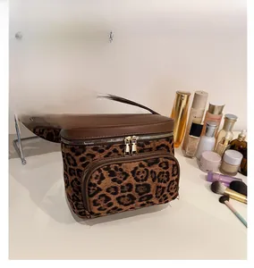 Close-up of leopard print velvet makeup bag with dual zippers and brown faux leather handle
