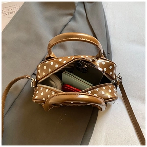 Detailed interior view of a brown polka dot Boston bag showing phone and wallet storage