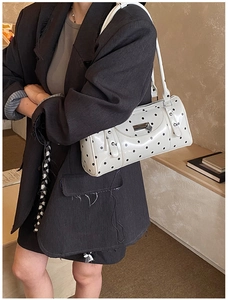 Close-up of a white polka dot bowling bag with a heart-shaped metal zipper charm