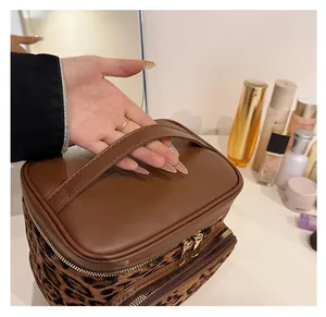 Close-up of leopard print makeup bag with golden double zipper and leather handle