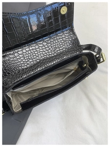 Detail of crocodile embossed patent leather bag with herringbone fabric lining and gold clasp