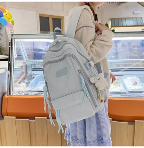 Close-up of light blue backpack with multi-layer pockets and cute plush bear charm