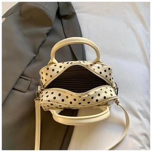 Close-up of the polka dot handbag interior with striped lining and zipper detail