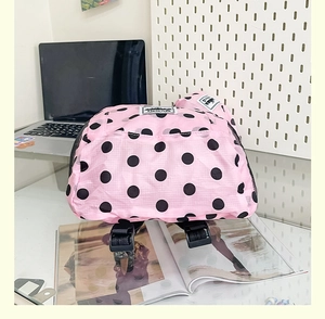 Detailed close-up of pink polka dot backpack showing nylon texture and mesh side pocket