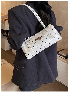 Detail of white polka dot baguette bag with silver studs and polished metal buckle
