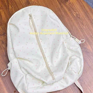 Detail showing the upgraded water-repellent fabric of the cream backpack with star pattern