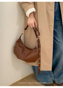 Detail of a dark brown matte leather half-moon bag featuring a minimalist retro style