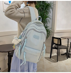Close-up of light blue student backpack with butterfly embroidery and cute plush pendant