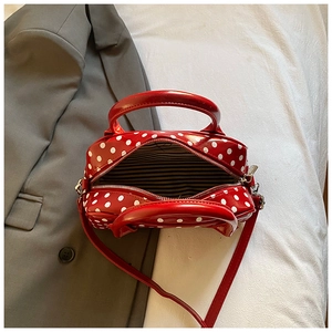 Close-up of red polka dot Boston bag with glossy finish and striped lining detail
