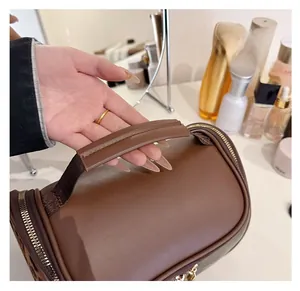 Close-up of double-layer brown PU leather toiletry bag with golden zippers and handle