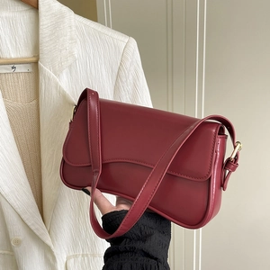 Close-up of a deep red leather shoulder bag with gold hardware and a flap closure design