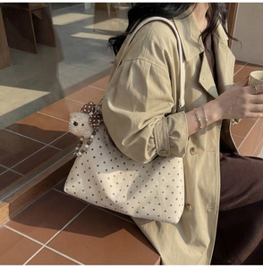 Detail of beige polka dot canvas crossbody bag with a cute plush bear charm accessory