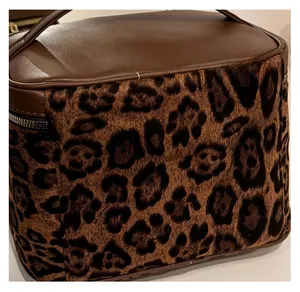 Detail of leopard print plush fabric and brown leather handle on cosmetic bag
