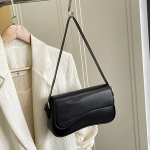 Detailed view of a black vintage shoulder bag styled on a white textured suit blazer