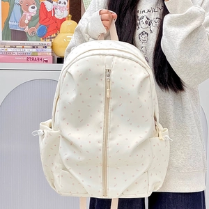 Detail of beige backpack with pink star patterns and central zipper pocket for school