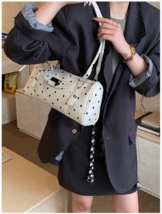Polka dot cylindrical shoulder bag with double straps shown in a lifestyle setting