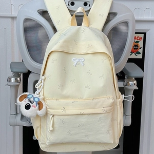 Minimalist light yellow backpack with white bow patterns and cute plush puppy charm