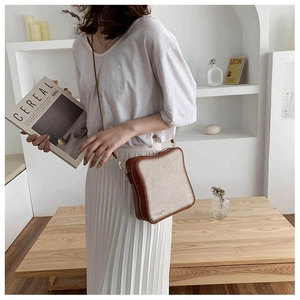 Detail shot of the bread-shaped crossbody bag worn by a model in a minimalist home setting