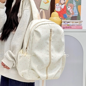 Detail of starry cream backpack showing side drawstring pocket and front zipper storage