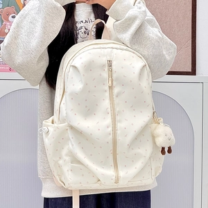 Close-up of beige star-patterned backpack with pink prints and a cute plush lamb charm