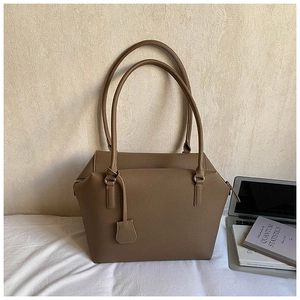 Minimalist brown pebbled calfskin tote bag with top handles and laptop on background