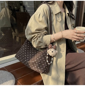 Close-up of retro brown polka dot hobo bag with teddy bear charm and beaded chain detail