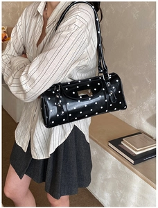 Détail du sac à bandoulière noir à pois avec finition brillante et porté épaule